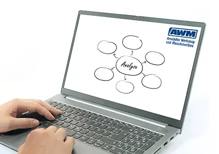 Hands typing on a laptop keyboard displaying a mind map with the central word Analyse and the AWM logo on screen.