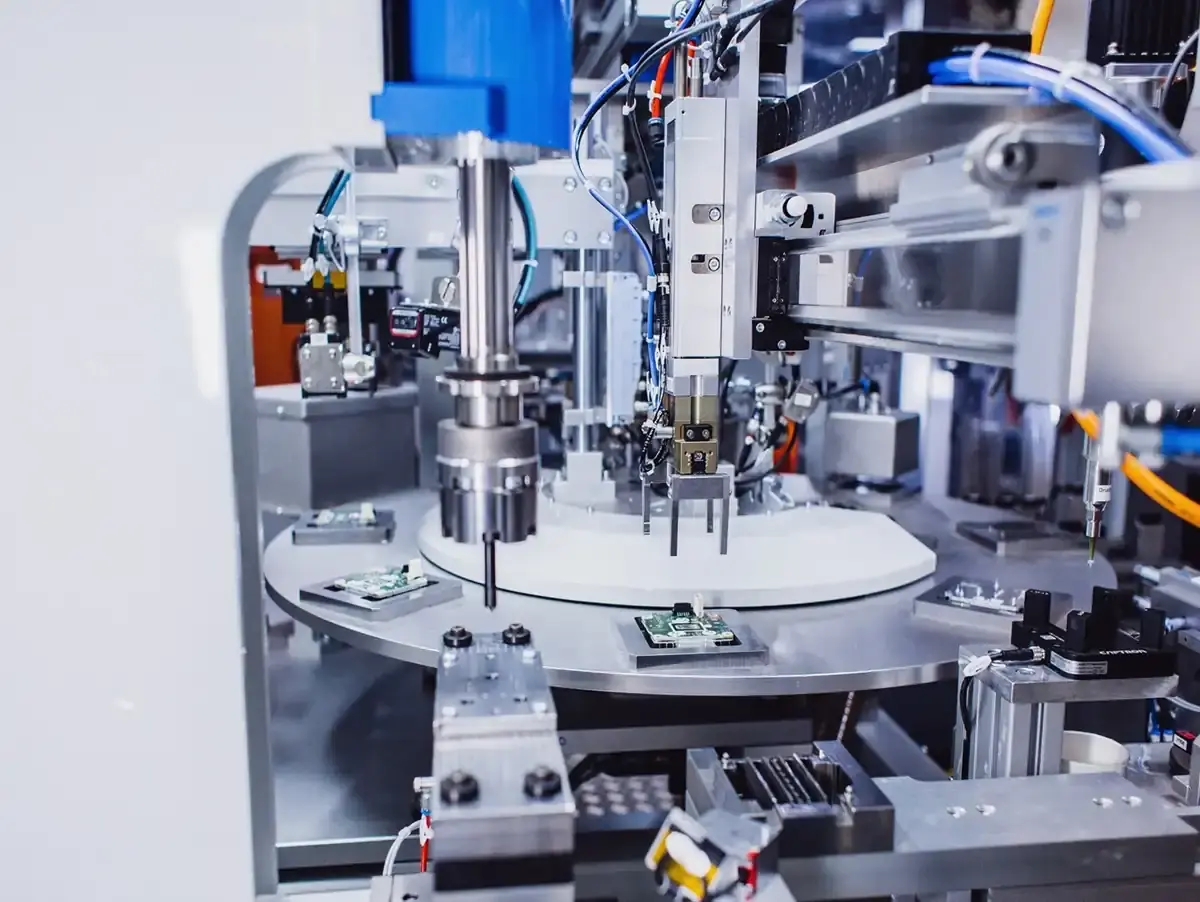 Close-up view of an automated rotary indexing assembly machine with integrated testing and processing stations for precise electronics and component manufacturing at AWM Arnstadt.