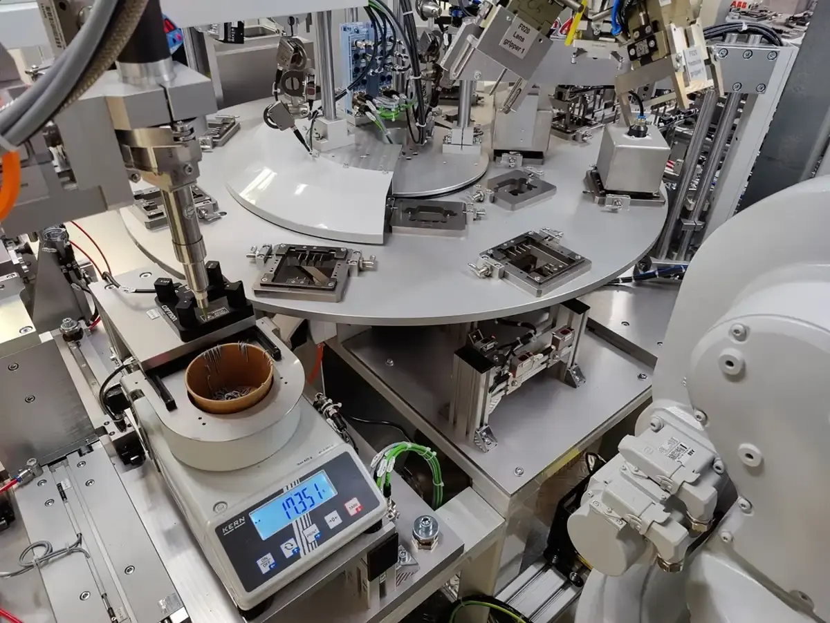 Detailed view of an automated testing station with an integrated digital precision scale, rotary indexing table, and gripper components for reliable quality control at AWM Arnstadt.