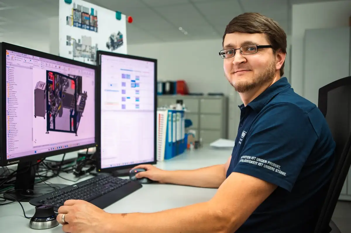 AWM employee in a branded polo shirt working on precise 3D modeling and development in a modern machine building office.