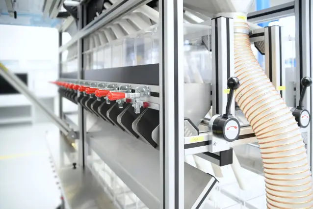 Detailed view of a separation station featuring red control handles, sorting chutes, and a flexible extraction hose.