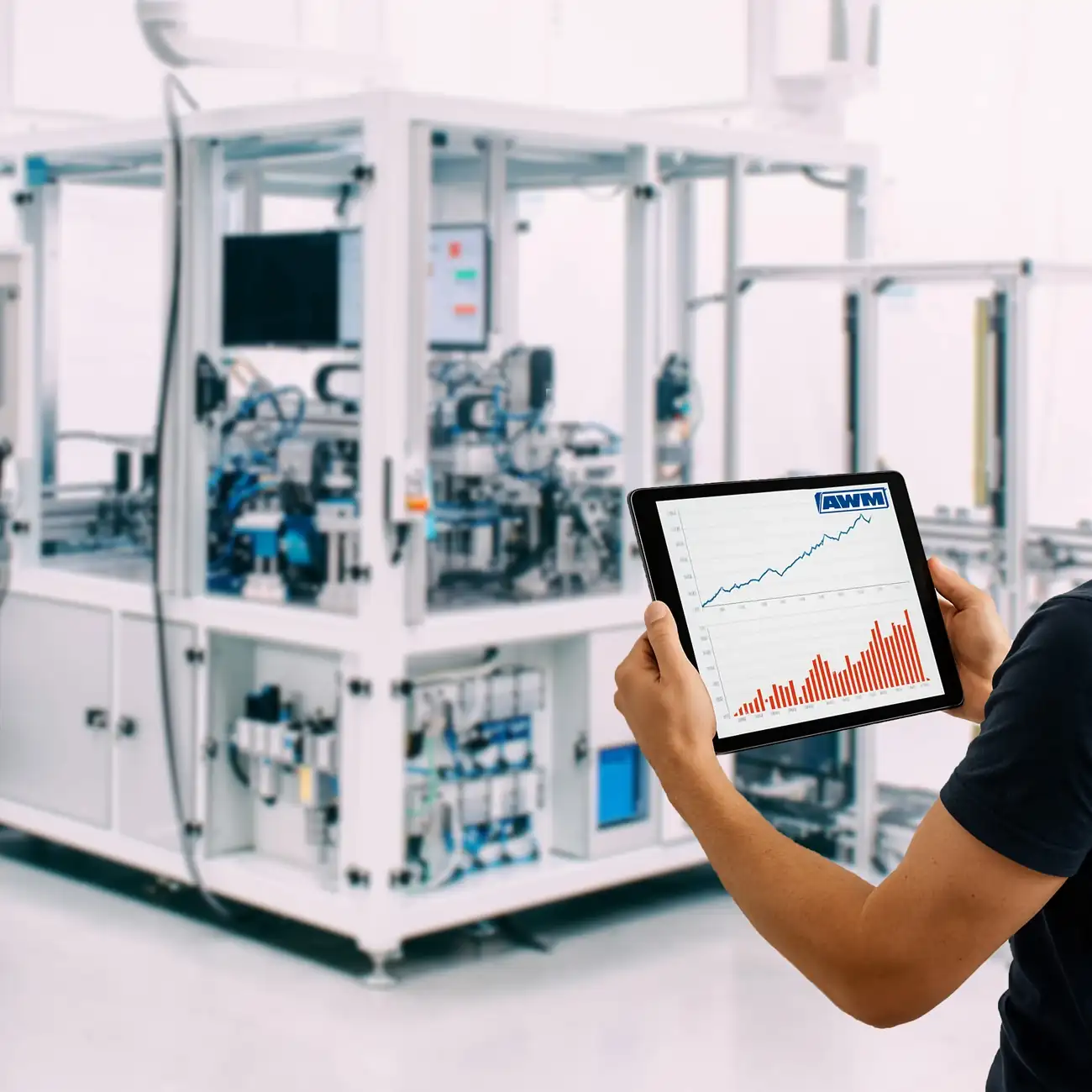 Operator monitoring real-time machine data and performance analytics in front of an AWM assembly cell on a tablet.